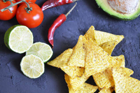 Mexican corn chips nachos with salsa dip on a black background with guacamole sauce, avacoda with lime and hot pepper tamato.の写真素材