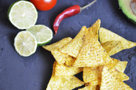 Mexican corn chips nachos with salsa dip on a black background with guacamole sauce, avacoda with lime and hot pepper tamato.の写真素材