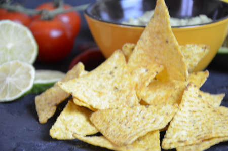 Mexican corn chips nachos with salsa dip on a black background with guacamole sauce, avacoda with lime and hot pepper tamato.の写真素材