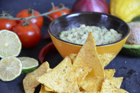 Mexican corn chips nachos with salsa dip on a black background with guacamole sauce, avacoda with lime and hot pepper tamato.の写真素材