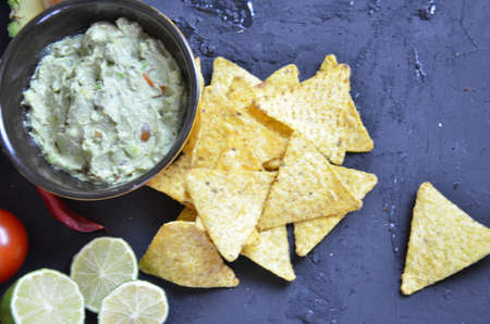 Mexican corn chips nachos with salsa dip on a black background with guacamole sauce, avacoda with lime and hot pepper tamato.の写真素材