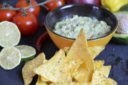 Mexican corn chips nachos with salsa dip on a black background with guacamole sauce, avacoda with lime and hot pepper tamato.の写真素材