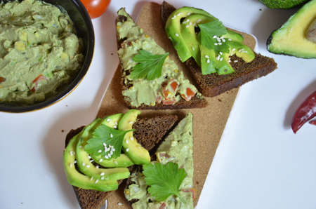 A delicious Bowl of Guacamole next to fresh ingredients on a table with tortilla chips and salsa. sandwich with guacamole, red hot pepper, lime, lemon, avocado.の写真素材