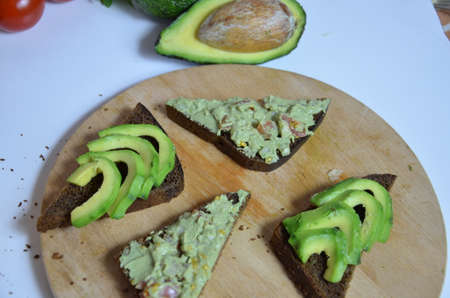 A delicious Bowl of Guacamole next to fresh ingredients on a table with tortilla chips and salsa. sandwich with guacamole, red hot pepper, lime, lemon, avocado.の写真素材