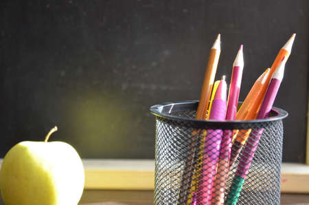 Back to school. pens, pencils, brushes in a glass against the background of a blackboard. School background with space for your textの写真素材