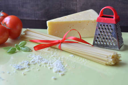composition of healthy food ingredients on yellow white background, top view. Ingredients for making macron, spaghetti, pasta. Tomatoes, basil, parmesan cheese, graterの写真素材