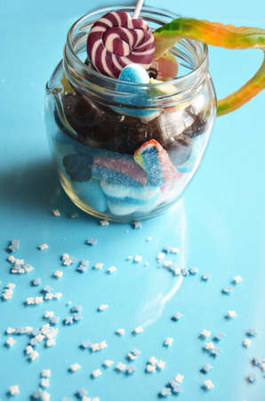 An assortment of colourful, festive sweets, blue marmalade in the shape of a heart on a blue background with a variety of caramels and candies, marshmallows. Abstract background. top view copy space.の写真素材