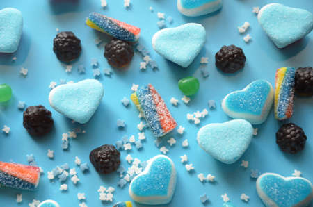An assortment of colourful, festive sweets, blue marmalade in the shape of a heart on a blue background with a variety of caramels and candies, marshmallows. Abstract background. top view copy space.の写真素材