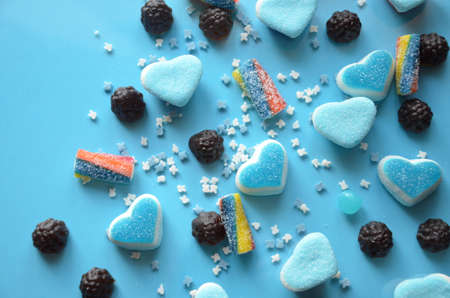 An assortment of colourful, festive sweets, blue marmalade in the shape of a heart on a blue background with a variety of caramels and candies, marshmallows. Abstract background. top view copy space.の写真素材
