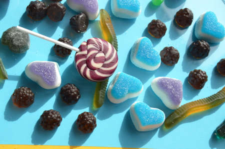 An assortment of colourful, festive sweets, blue marmalade in the shape of a heart on a blue background with a variety of caramels and candies, marshmallows. Abstract background. top view copy space.の写真素材