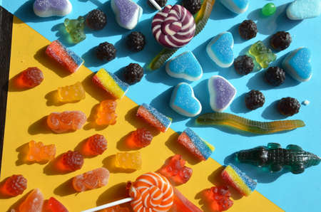 An assortment of colourful, festive sweets, blue marmalade in the shape of a heart on a blue background with a variety of caramels and candies, marshmallows. Abstract background. top view copy space.の写真素材