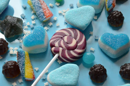 An assortment of colourful, festive sweets, blue marmalade in the shape of a heart on a blue background with a variety of caramels and candies, marshmallows. Abstract background. top view copy space.の写真素材