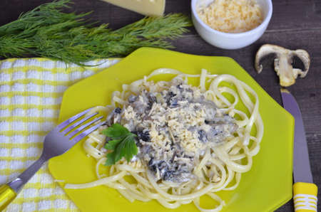 Pasta fettuccine with mushrooms and fried chicken ham in creamy cheese sauce on a dark wooden background.の写真素材