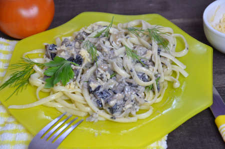 Pasta fettuccine with mushrooms and fried chicken ham in creamy cheese sauce on a dark wooden background.の写真素材
