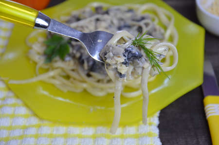 Pasta fettuccine with mushrooms and fried chicken ham in creamy cheese sauce on a dark wooden background.の写真素材