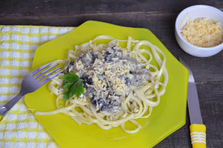 Pasta fettuccine with mushrooms and fried chicken ham in creamy cheese sauce on a dark wooden background.の写真素材