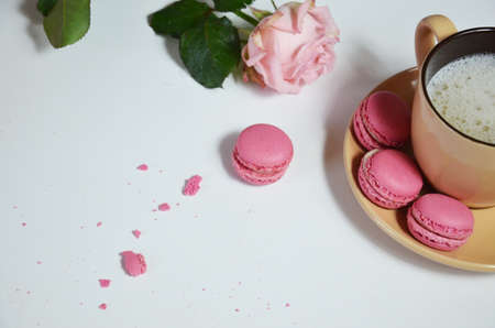 The inscription is a good morning over a cup of Cappuccino on a white wooden table with pink rose flowers with a frosty macaroni / Good morning with coffeeの写真素材