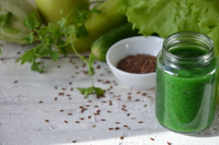 Detox diet. Green smoothie with different vegetables on wooden background copy space. diet vegitarians healthy low calorie food. salad, greens, green apple chia or flax linen seedsの写真素材
