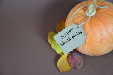 Thanksgiving Day. Pumpkin, pumpkin with autumn leaves and apples. Autumn harvest on a brown background. Happy Thanksgiving Lettering set table for celebration. fork and knife.の写真素材