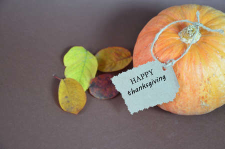 Thanksgiving Day. Pumpkin, pumpkin with autumn leaves and apples. Autumn harvest on a brown background. Happy Thanksgiving Lettering set table for celebration. fork and knife.の写真素材