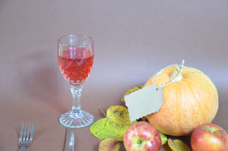 Thanksgiving Day. Pumpkin, pumpkin with autumn leaves and apples. Autumn harvest on a brown background. Happy Thanksgiving Lettering set table for celebration. fork and knife still life with bottle glass of red wine/の写真素材