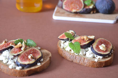 Sandwiches with ricotta, fresh figs, walnuts and honey. Canape or crostini with toasted baguette, cheese, jam, Delicious appetizer, ideal as an aperitif. Selective focusの写真素材