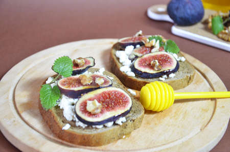 Sandwiches with ricotta, fresh figs, walnuts and honey. Canape or crostini with toasted baguette, cheese, jam, Delicious appetizer, ideal as an aperitif. Selective focusの写真素材