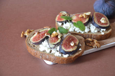Sandwiches with ricotta, fresh figs, walnuts and honey. Canape or crostini with toasted baguette, cheese, jam, Delicious appetizer, ideal as an aperitif. Selective focusの写真素材