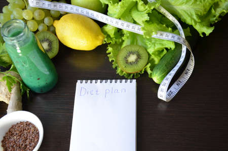 Diet plan, menu or program, tape measure, diet food, weight loss and detox concept, top view, green vegetables and fruits with green smoothie on a dark a notepad, Lemon Chia Seeds, Ginger.の写真素材