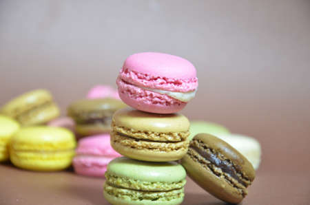 Colourful tasty macaroons in a row. macaroons of different colors on a brown background.
