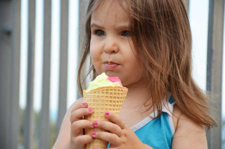 Cute Toddler Girl Eating Ice Cream outdoors in blue dressの写真素材