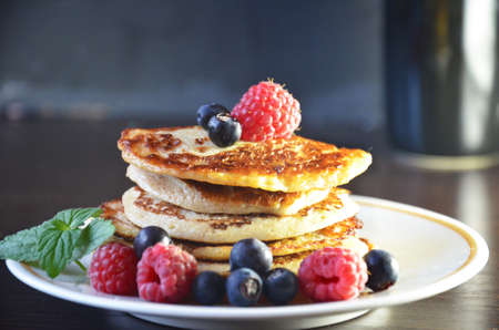 Pancakes with berries and maple syrup with raspberries and blueberries on a black background.の写真素材