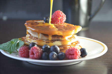 Pancakes with berries and maple syrup with raspberries and blueberries on a black background.の写真素材