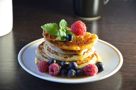 Pancakes with berries and maple syrup with raspberries and blueberries on a black background.の写真素材