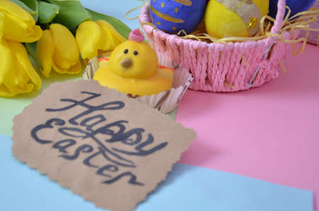 Easter, Easter egg color vibrant, spring Orthodox holiday. colorful decorated eggs in a pink basket on a background of different colors. inscription happy easter, gift, chicken, yellow tulips.の写真素材