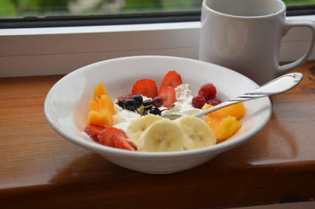 Healthy breakfast or snack curd with fruit and nuts. The concept of nutrition for weight loss. Keto breakfast. Keto lunch idea. cottage cheese or yogurt with berries on a window cup of coffee or tea.の写真素材