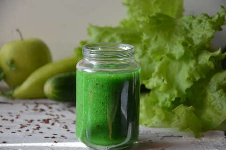 Detox diet. Green smoothie with different vegetables on wooden background copy space. diet vegitarians healthy low calorie food. salad, greens, green apple chia or flax linen seedsの写真素材