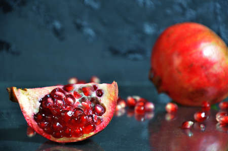 ripe pomegranate with leaves on a black board on a dark backgroundの写真素材