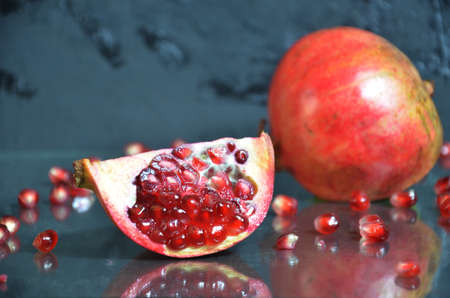 ripe pomegranate with leaves on a black board on a dark backgroundの写真素材