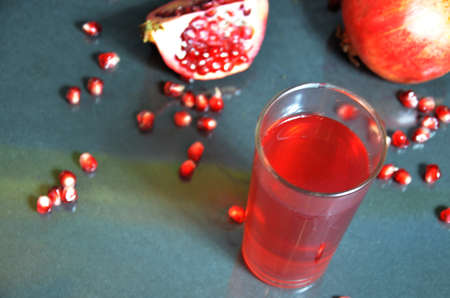 A glass of pomegranate juice with fresh pomegranate fruits on dark blackの写真素材