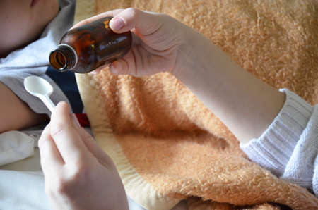Mom pours potion for sink son.の写真素材