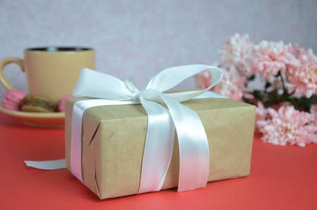 Mothers day or women's Day concept - box with a gift a beige cup of cappuccino beautiful white-pink...