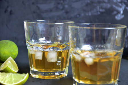 Drink cold tea with ice cubes and mint in two glass goblets a dark black background. Alcoholic or non-alcoholic mahito. whiskey or scotch tape, with lime or lemonの写真素材