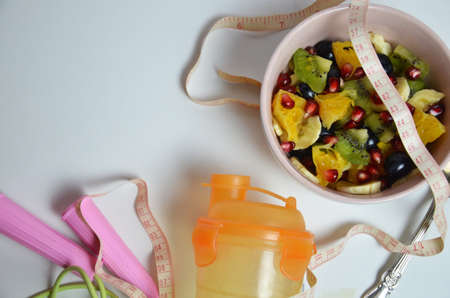 Fitness, healthy fruits, Fresh healthy salad, diet and active lifestyles Concept, dumbbells, fresh fruits, bottle for water, measure centimeter, jump rope on a white background . copy space for textの写真素材