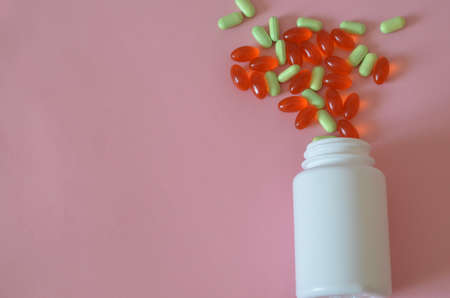 Assorted pharmaceutical medicine pills, tablets and capsules and bottle on pink background. Copy space for text.の写真素材