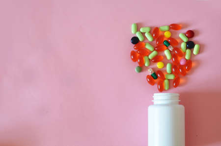 Assorted pharmaceutical medicine pills, tablets and capsules and bottle on pink background. Copy space for text.の写真素材