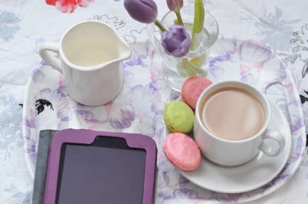 Tray with paper sketchbook, smartphone and spring flowers on pink bedding. Relaxing, or working, or writing diary or blog in bed at home. with tablet.の写真素材