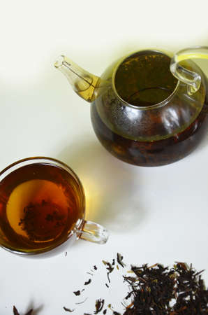 teapot and cup of tea on a white background with dry tea leaves with cinnamon and aniseの写真素材