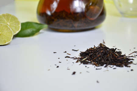 Transparent teapot with black tea, dry tea brewing on the table, bergamot slices, or lemon or lime on a white backgroundの写真素材