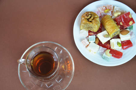 Tasty oriental sweets baklava, turkish delight on a plate on a dark black brown background and glasses of tea.の写真素材